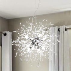 a white chandelier hanging from the ceiling in a room with curtains and drapes