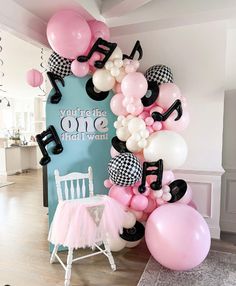 the balloon arch is decorated with musical notes and pink, white, and black balloons