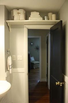 an open door leading to a bathroom with white walls and wood flooring on the other side