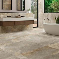 a bathroom with a tub, sink and large window overlooking the trees in the background