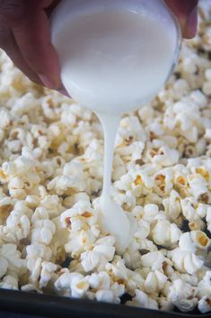 someone pouring milk into a bowl of popcorn