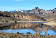 the mountains are reflected in the still water