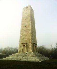 an obelisk in the middle of a grassy area with stairs leading up to it