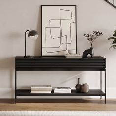 a black shelf with books and vases on it in front of a stair case