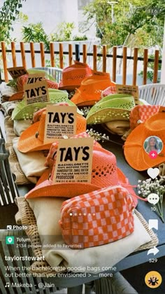 many hats are sitting on top of each other at a table with tags attached to them