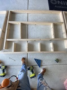 someone is standing in front of a shelf made out of wooden planks and plywood