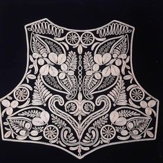 an intricately designed piece of cloth with flowers and leaves on black background, in the shape of a vest