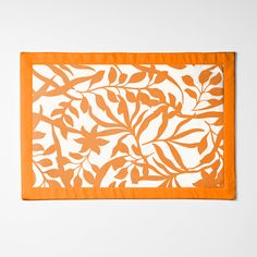 an orange and white placemat with leaves on it in front of a white wall