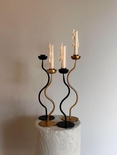 two black and gold candlesticks on top of a white cake