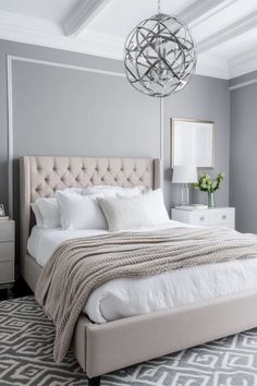 a bedroom with gray walls and white bedding, chandelier and rugs