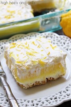 a piece of cake on a white plate with silverware and lemons in the background