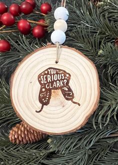 a wooden ornament hanging from a christmas tree with berries and pine cones around it