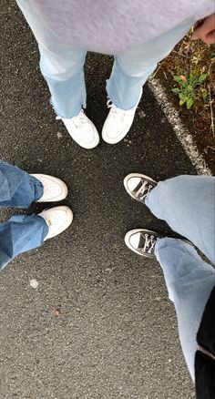 three people standing in a circle on the street with their feet crossed and one person wearing white shoes