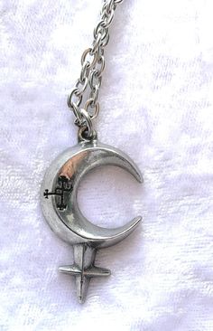 a silver necklace with a crescent and cross on it