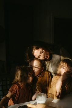 a woman and two children are sitting at a table with milk in front of them