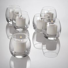 four clear glass vases filled with white candles