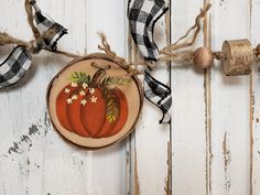 a wooden slice with some flowers on it hanging from a rope next to two rolls of twine