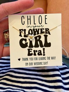 a woman holding up a card with the words flower girl on it and a ring in her hand