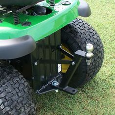 a green four - wheeled vehicle parked in the grass with its front wheels down and two large tires on it