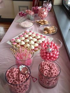 pink and white cupcakes are on display in glass containers, along with other desserts