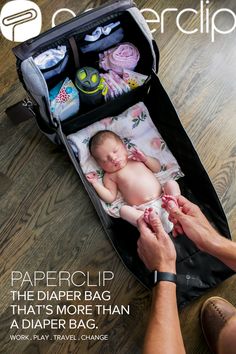 a person holding a baby in an open suitcase on the floor with other items inside