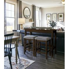 a living room filled with furniture next to a dining table and two bar stools