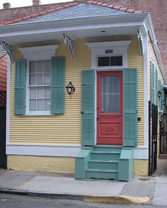 a yellow house with blue shutters and a red door