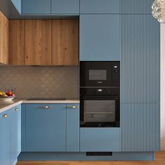 a kitchen with blue cabinets and white counter tops is pictured in this image, there are two ovens on each side of the wall