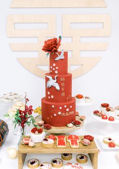 a red and white cake on a table with cupcakes