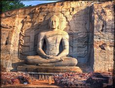 a large buddha statue sitting in front of a stone wall