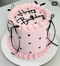 a pink birthday cake with black hearts on it