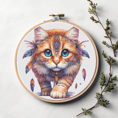 a cross stitch pattern with a cat in the center and feathers on its head, sitting next to a plant