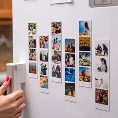 a refrigerator door with magnets on it and pictures hanging on the front, behind which is a woman's hand