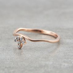 a rose gold ring with two diamonds on it's side, sitting on a concrete surface