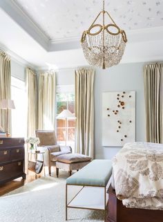 a bedroom with a chandelier hanging from the ceiling and a bed in front of a window