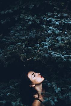 a woman in the woods looking up at something with her eyes closed and nose open