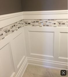 the corner of a room with white paneling and gray wall tiles on the walls