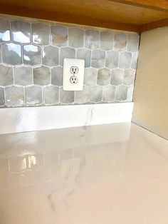 a white counter top sitting under a wooden shelf next to a light switch on a wall