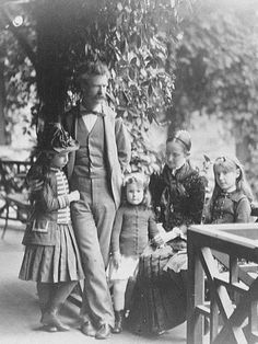 an old black and white photo of a man standing with two small children in front of him