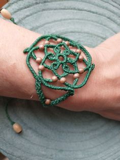 I have made this bracelet in grass green combined with a toasted beige color present in the wooden beads that adorn the bracelet. It is a bracelet with a mandala design and boho style, very light and attractive. The closure is sliding, so the bracelet can be adjusted to the desired size. I have finished it with two raw-colored wooden beads that hang from the ends of the chain. The width of the widest part of the bracelet is 5 cm (1.96 in) approx. The maximum length of the chain is approximately Handmade Green Bohemian Braided Bracelets, Handmade Green Bohemian Braided Bracelet, Bohemian Green Braided Bracelets For Festivals, Green Bohemian Bracelets With Adjustable Cord, Green Macrame Bohemian Bracelets, Green Bohemian Macrame Bracelets, Green Macrame Friendship Bracelets, Green Macrame Beaded Bracelets For Festivals, Adjustable Green Bracelet With Wooden Beads