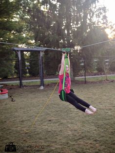 a girl is swinging on a rope in the park