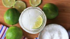 an overhead view of a margarita with limes around it