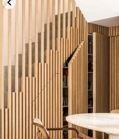 a dining room table and chairs with wooden slats on the wall