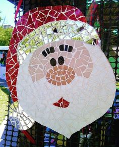 a mosaic santa face hanging on a fence