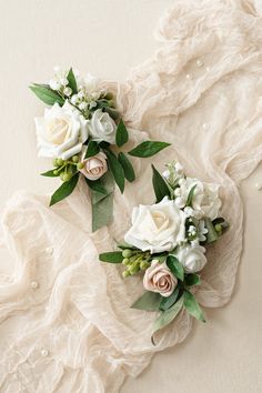 two bridal bouquets with white flowers and greenery on a lace tablecloth