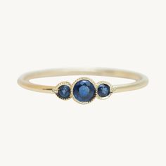 three stone ring in yellow gold with blue sapphires on the sides and diamond accents