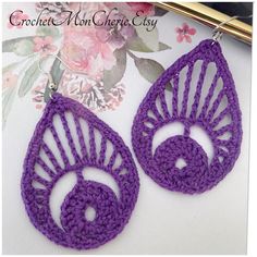 purple crochet earrings with tear shaped design on top and bottom, in front of floral background