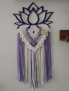 a purple and white crochet wall hanging with a lotus decoration on the side