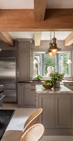 a large kitchen with an island in the middle and two pendant lights hanging from the ceiling