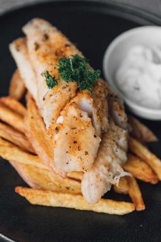 a black plate topped with chicken and french fries